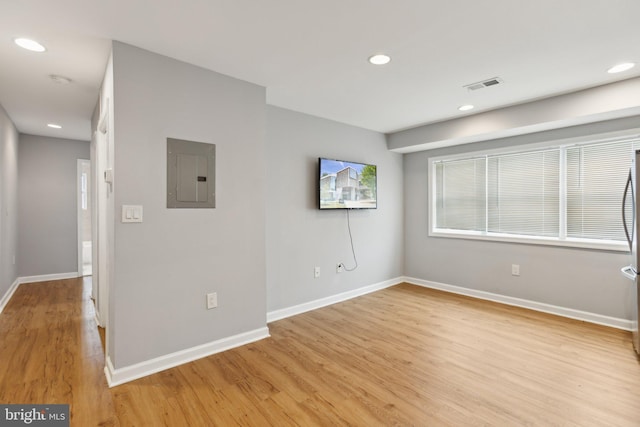 unfurnished room featuring electric panel and light hardwood / wood-style floors