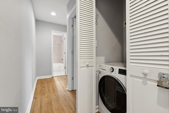 laundry area with washer / dryer and light hardwood / wood-style flooring