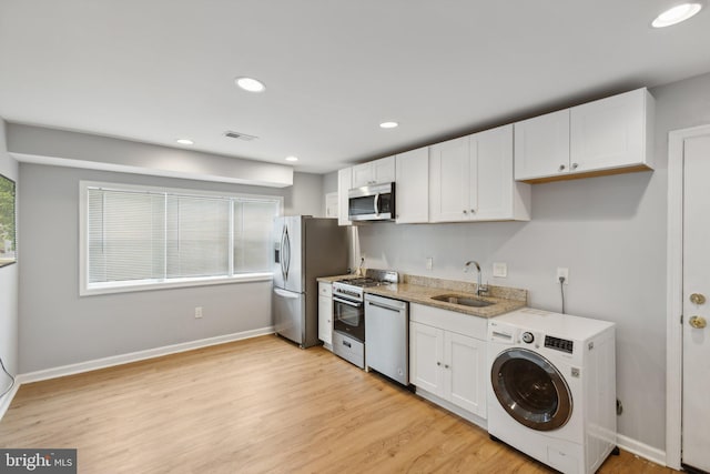 kitchen featuring white cabinetry, stainless steel appliances, sink, light hardwood / wood-style flooring, and washer / clothes dryer