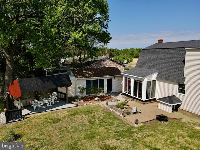 rear view of property featuring a sunroom, a yard, and a deck