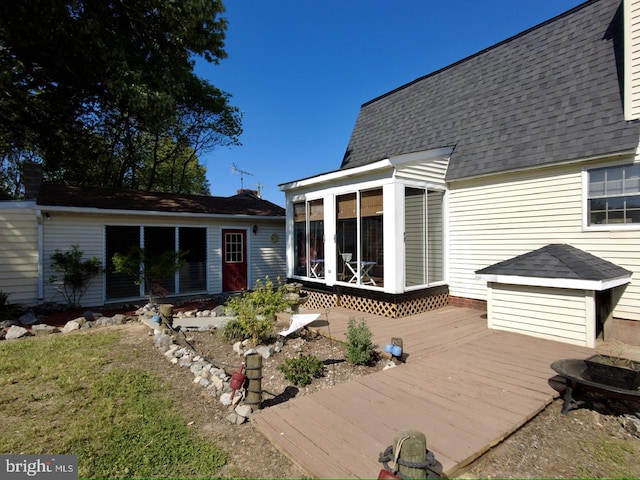 rear view of house featuring a sunroom and a deck