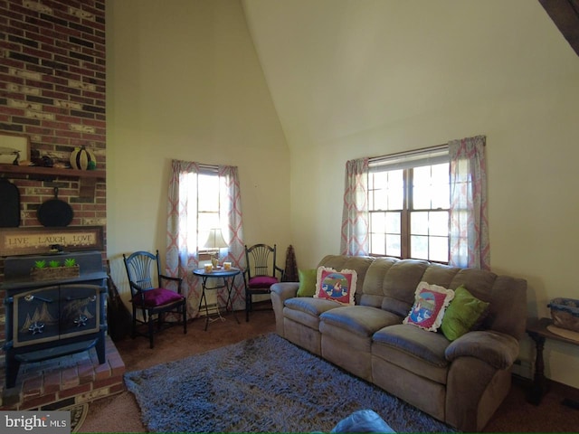 living room featuring high vaulted ceiling, a wood stove, carpet floors, and a wealth of natural light