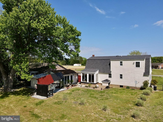 back of house with a sunroom, a storage shed, central air condition unit, and a yard