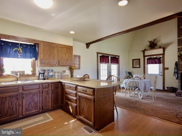 kitchen with kitchen peninsula, plenty of natural light, and light hardwood / wood-style floors