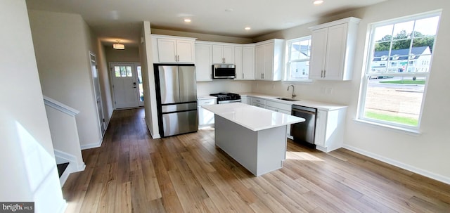 kitchen featuring sink, a center island, light hardwood / wood-style flooring, stainless steel appliances, and white cabinets