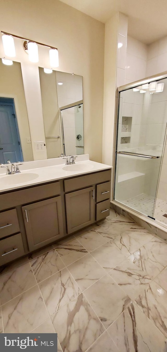 bathroom featuring a shower with shower door and vanity