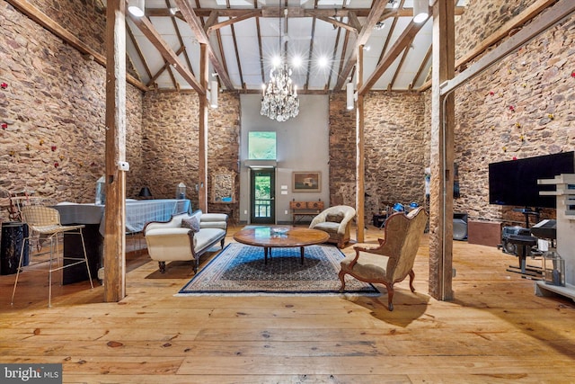 living area with a chandelier, beam ceiling, hardwood / wood-style flooring, and high vaulted ceiling