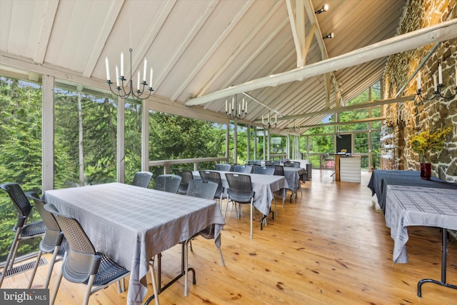 exterior space featuring a chandelier, vaulted ceiling with beams, and a wealth of natural light