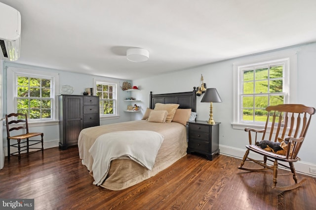 bedroom with a wall mounted AC and dark wood-type flooring