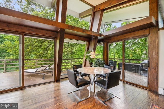 sunroom featuring beam ceiling, plenty of natural light, and a baseboard heating unit