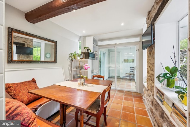 dining area featuring beam ceiling and light tile patterned floors