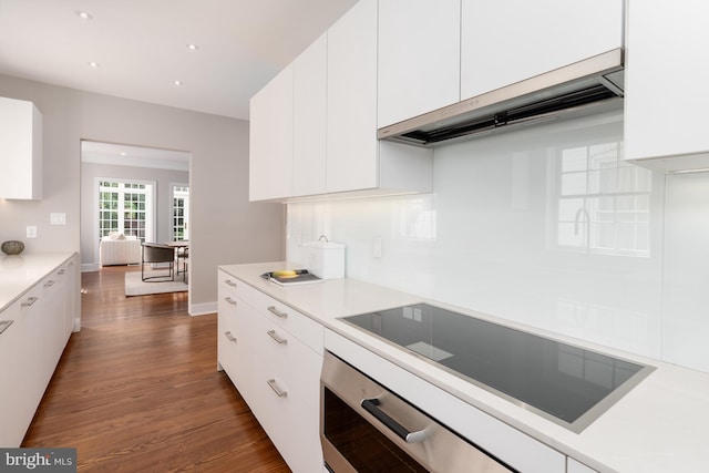 kitchen featuring dark hardwood / wood-style flooring, wall oven, white cabinets, black electric cooktop, and exhaust hood