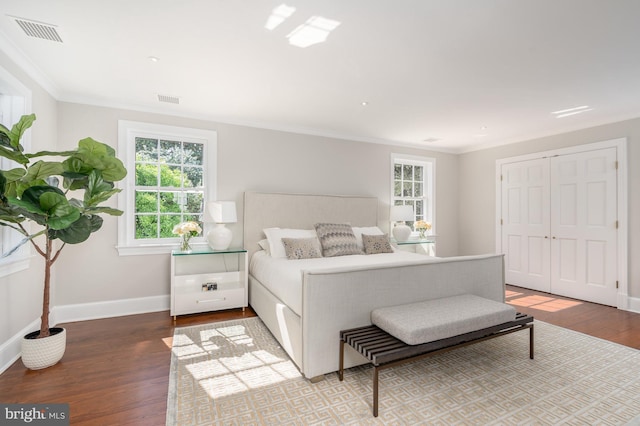 bedroom with hardwood / wood-style flooring, crown molding, and a closet