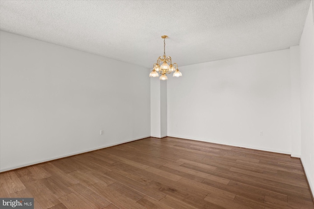 unfurnished room featuring a chandelier, wood-type flooring, and a textured ceiling