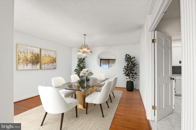 dining room featuring a notable chandelier, light hardwood / wood-style floors, and a textured ceiling