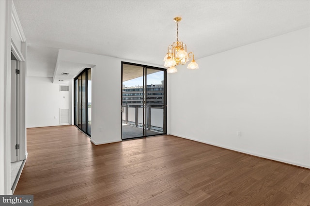 empty room with floor to ceiling windows, dark wood-type flooring, a textured ceiling, and an inviting chandelier