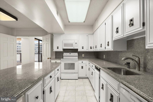 kitchen featuring dark stone countertops, white cabinetry, sink, and white appliances