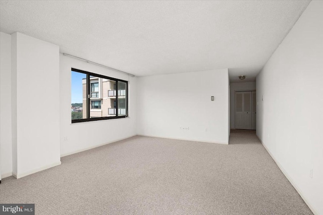 spare room featuring a textured ceiling and light carpet