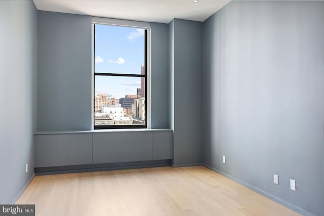 empty room featuring baseboards, light wood finished floors, and a city view