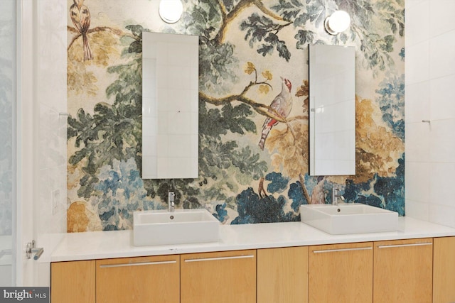 bathroom with double vanity, a sink, and wallpapered walls