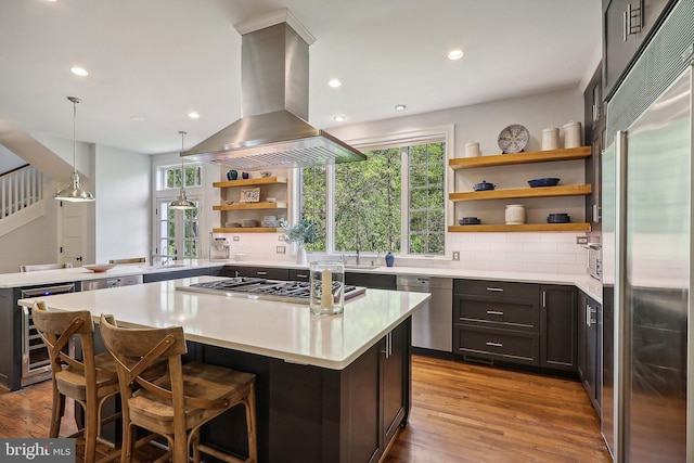 kitchen featuring pendant lighting, stainless steel appliances, island exhaust hood, wine cooler, and a kitchen island