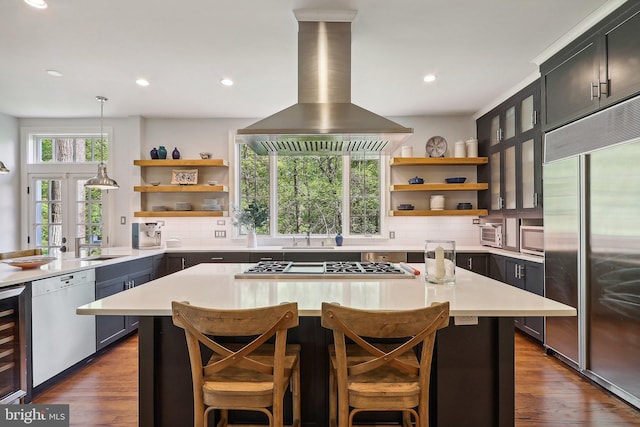 kitchen with pendant lighting, appliances with stainless steel finishes, a center island, island range hood, and a kitchen bar