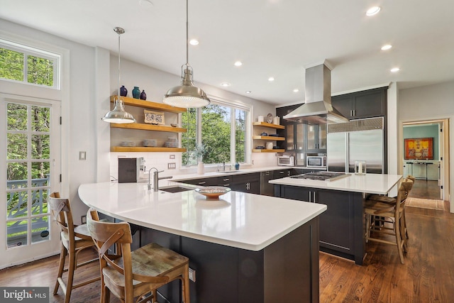 kitchen with island exhaust hood, stainless steel appliances, a breakfast bar area, and a large island with sink