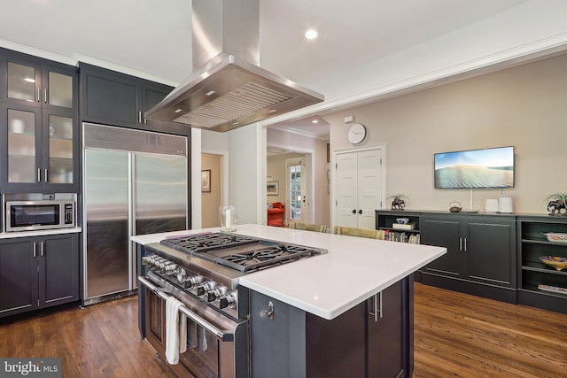 kitchen featuring dark wood-type flooring, a kitchen island, island exhaust hood, premium appliances, and a kitchen bar