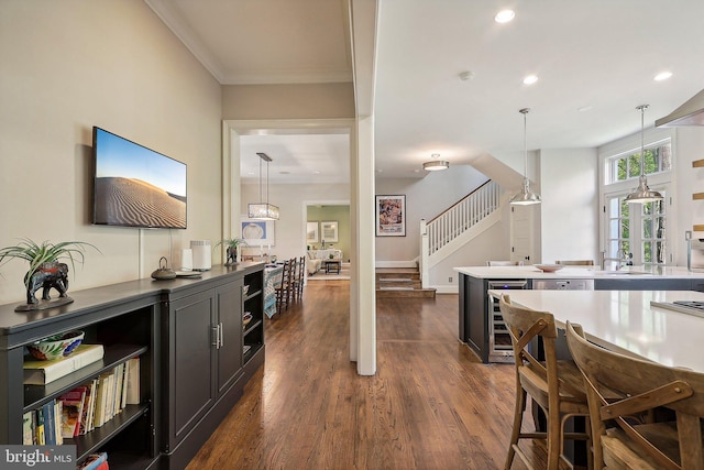 interior space featuring crown molding, beverage cooler, dark hardwood / wood-style flooring, and hanging light fixtures