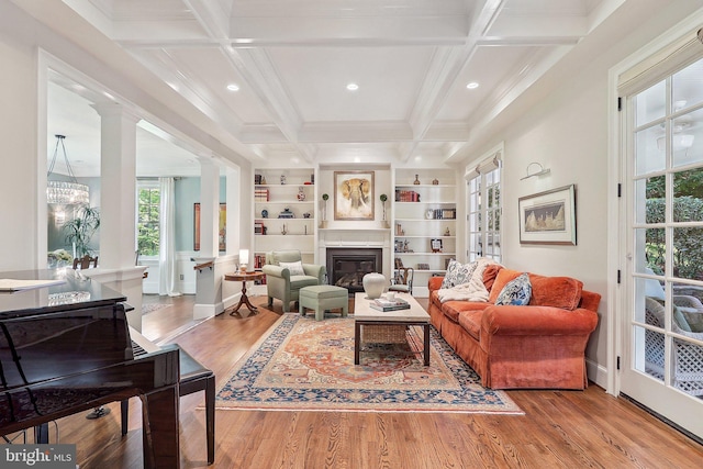 living room featuring coffered ceiling, ornate columns, built in features, beam ceiling, and hardwood / wood-style floors