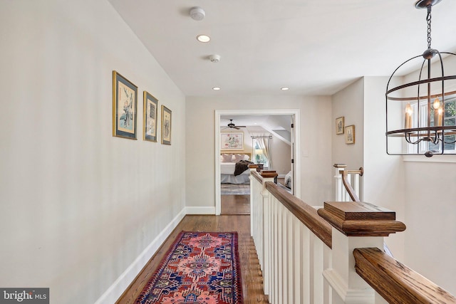 corridor with hardwood / wood-style floors and a notable chandelier