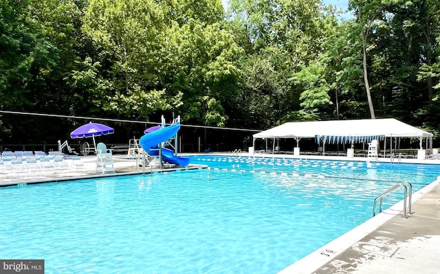 view of swimming pool featuring a water slide and a patio area