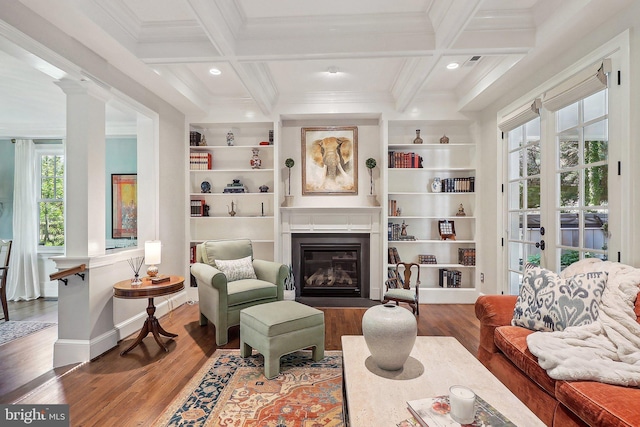 living room featuring beamed ceiling, hardwood / wood-style flooring, ornamental molding, coffered ceiling, and built in shelves