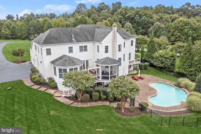 back of property featuring a chimney, a wooden deck, a patio area, roof with shingles, and a sunroom