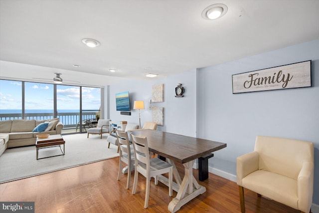 dining room featuring hardwood / wood-style flooring, ceiling fan, and a water view