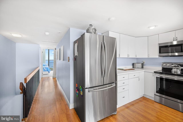 kitchen featuring appliances with stainless steel finishes, light hardwood / wood-style floors, and white cabinets