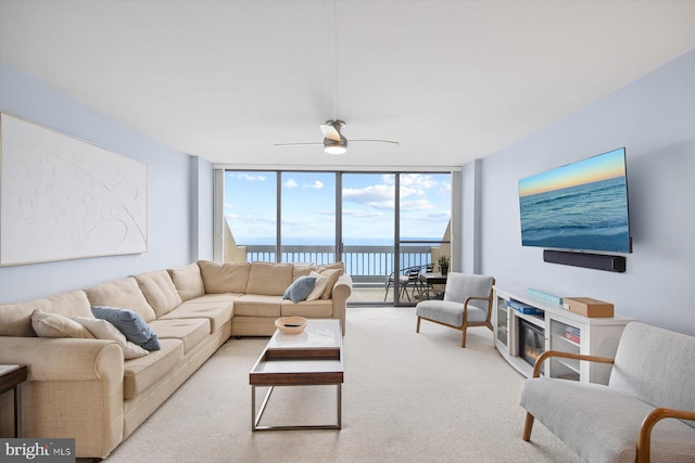 living room featuring a water view, ceiling fan, and expansive windows