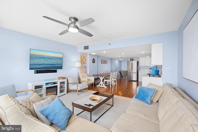 living room with light hardwood / wood-style floors, ceiling fan, and a fireplace