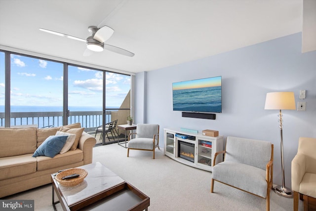 carpeted living room with a water view, a wall of windows, and ceiling fan