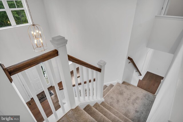 stairs featuring baseboards, wood finished floors, visible vents, and a notable chandelier