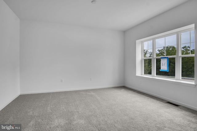 unfurnished room featuring carpet, visible vents, and baseboards