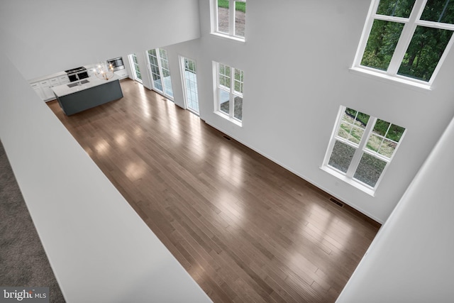 living area with a towering ceiling, dark wood-style floors, and visible vents