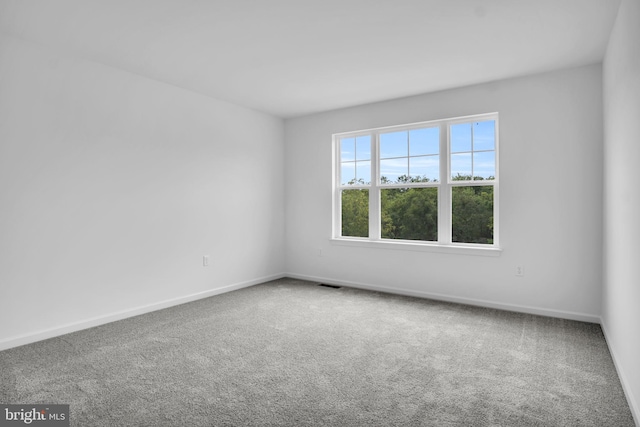 unfurnished room featuring carpet, visible vents, and baseboards