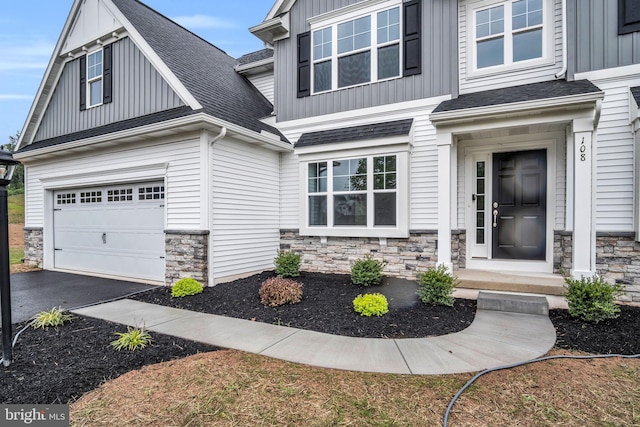 entrance to property with stone siding, a shingled roof, board and batten siding, and aphalt driveway