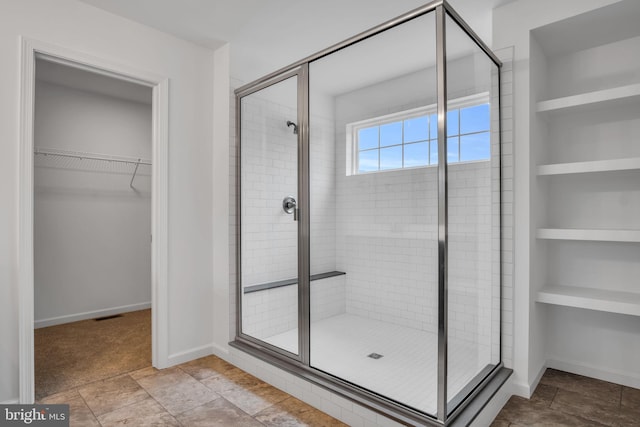 full bath with a stall shower, baseboards, visible vents, a walk in closet, and built in shelves