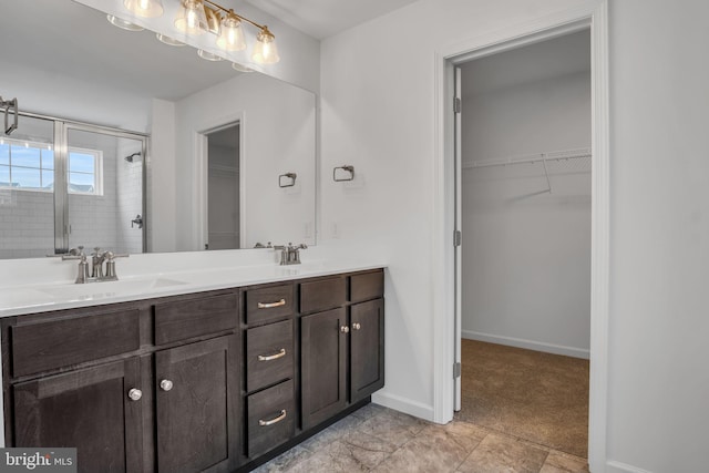 full bath with a stall shower, a walk in closet, a sink, and baseboards