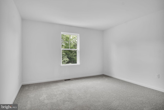 carpeted spare room with visible vents and baseboards