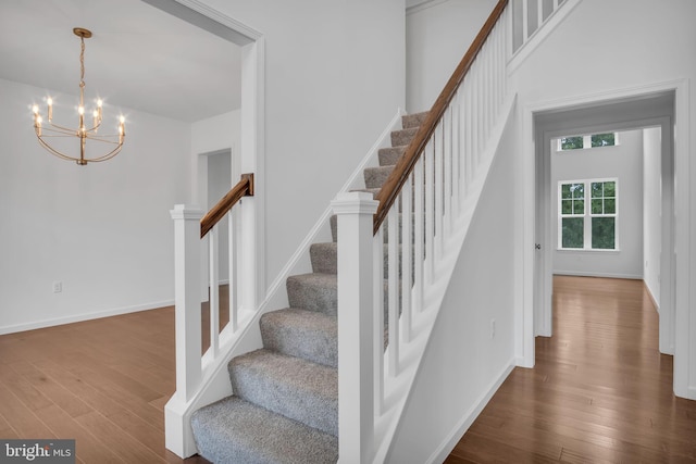 stairway with a notable chandelier, baseboards, and wood finished floors