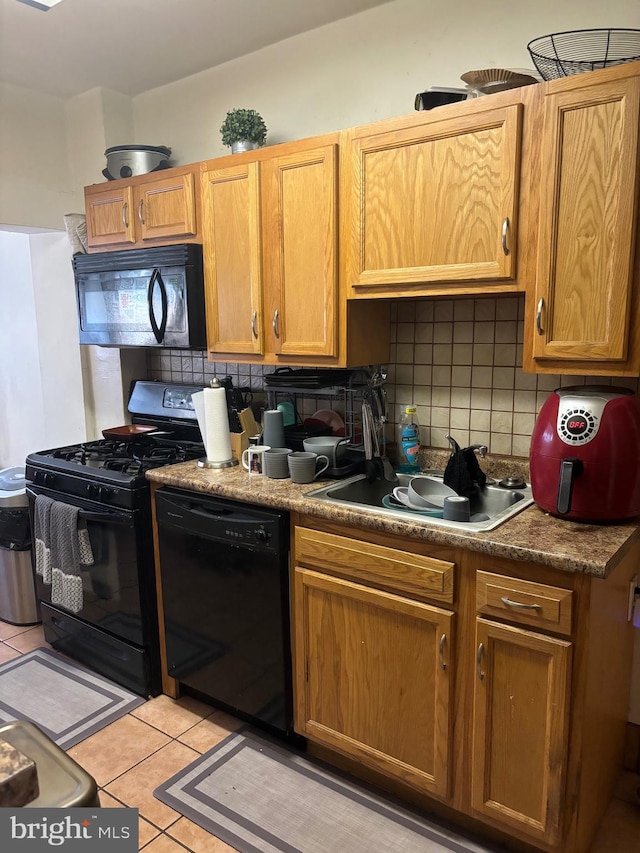 kitchen featuring backsplash, sink, light tile patterned flooring, and black appliances