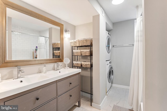 bathroom with tile flooring, dual sinks, vanity with extensive cabinet space, and stacked washer and dryer